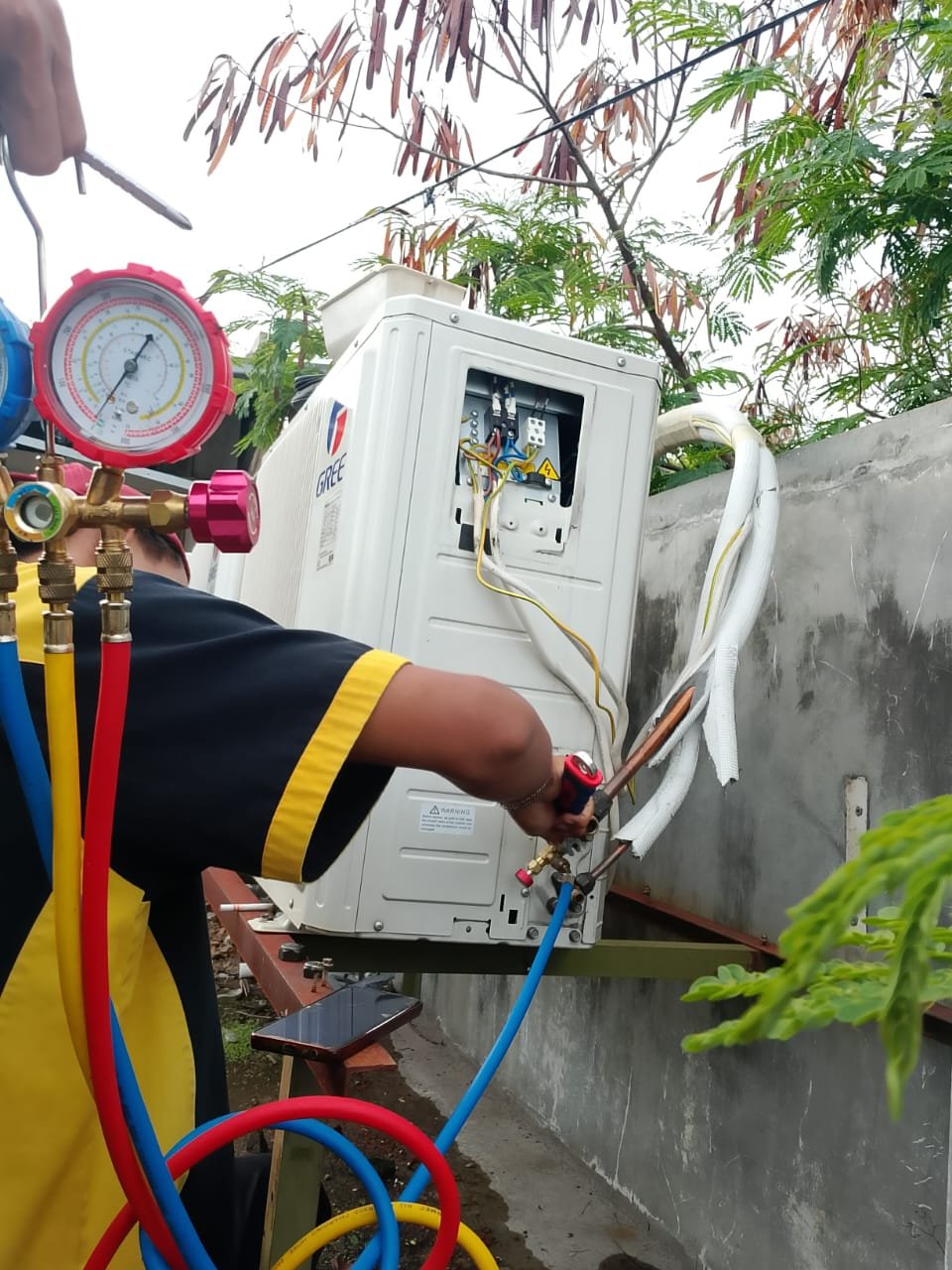 Teknisi sedang menambal kebocoran pipa AC